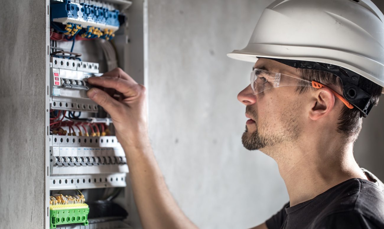 Man, an electrical technician working in a switchboard with fuses. Installation and connection of electrical equipment.